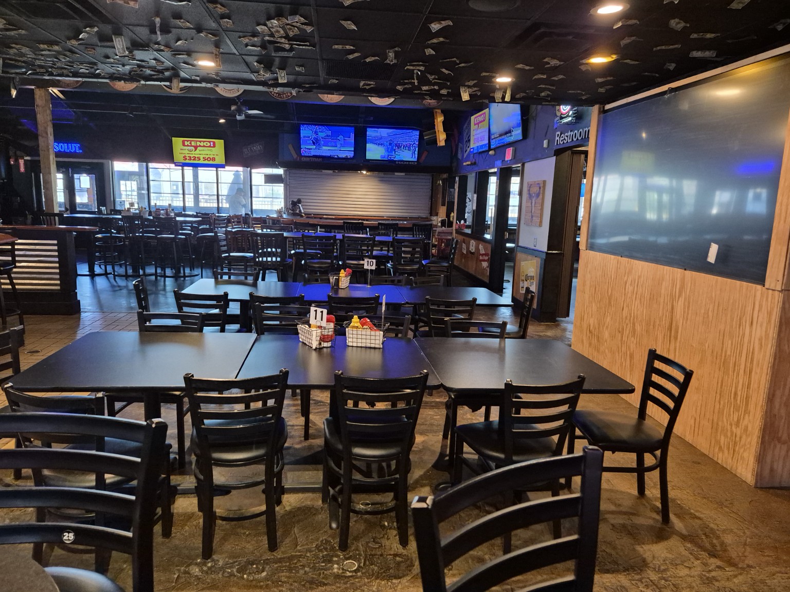 Canton Icehouse dining area with rows of tables and chairs beneath the ceiling covered in dollar bills.