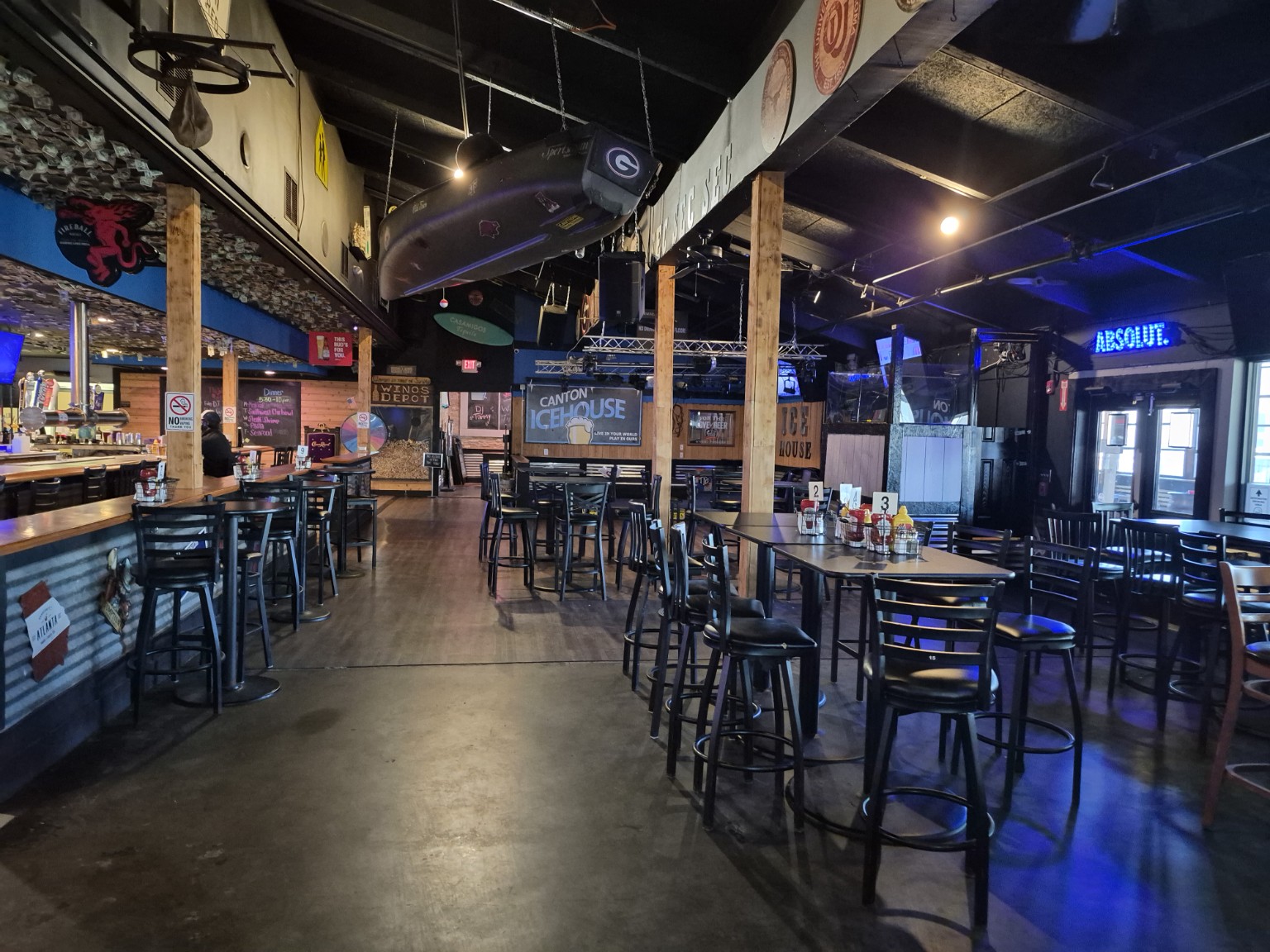 Wide interior view of Canton Icehouse with its bar, high-top tables and suspended canoe.